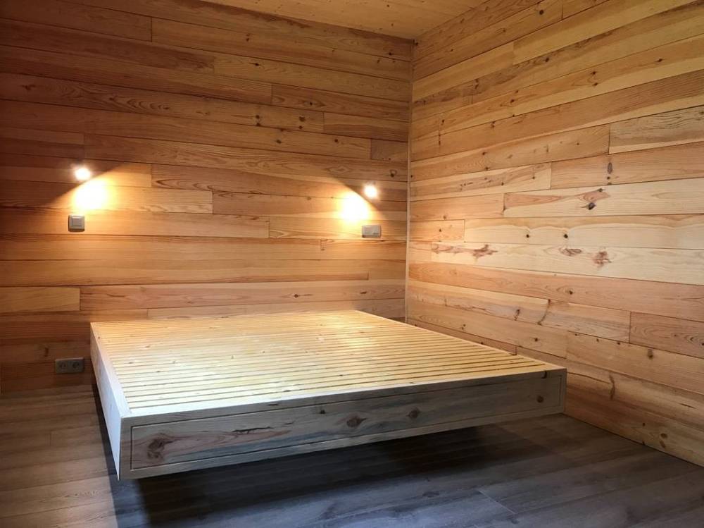 Mur d’une chambre en volige mi-bois et lit en pin brut